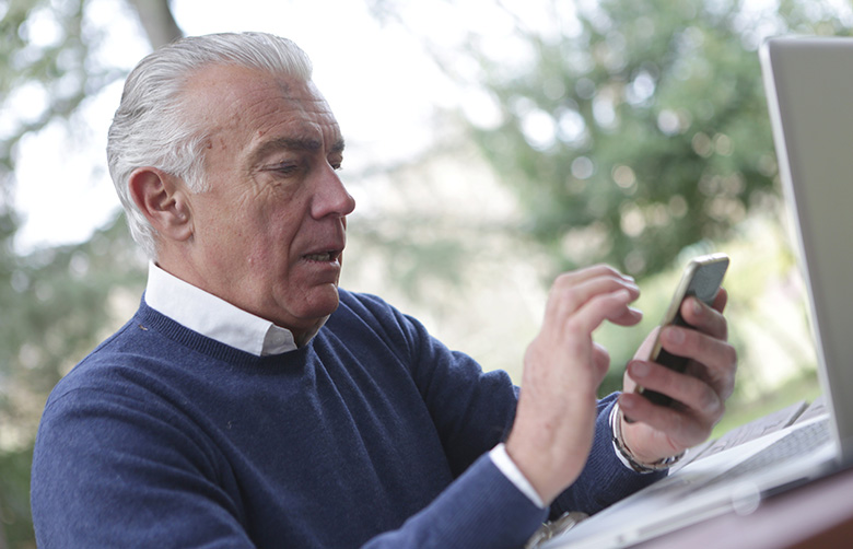 Senior mit Mobiltelefon und Laptop