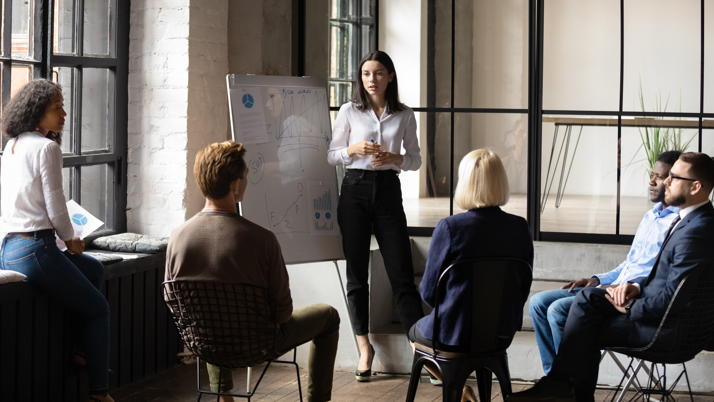 Selbstbewusste Business-Trainer-Coach-Leiterin gibt Flipchart-Präsentation, berät Kunden und unterrichtet Mitarbeiter, Schulungsteam-Leute, die beim Marketing-Workshop-Konzept die Strategie erklären