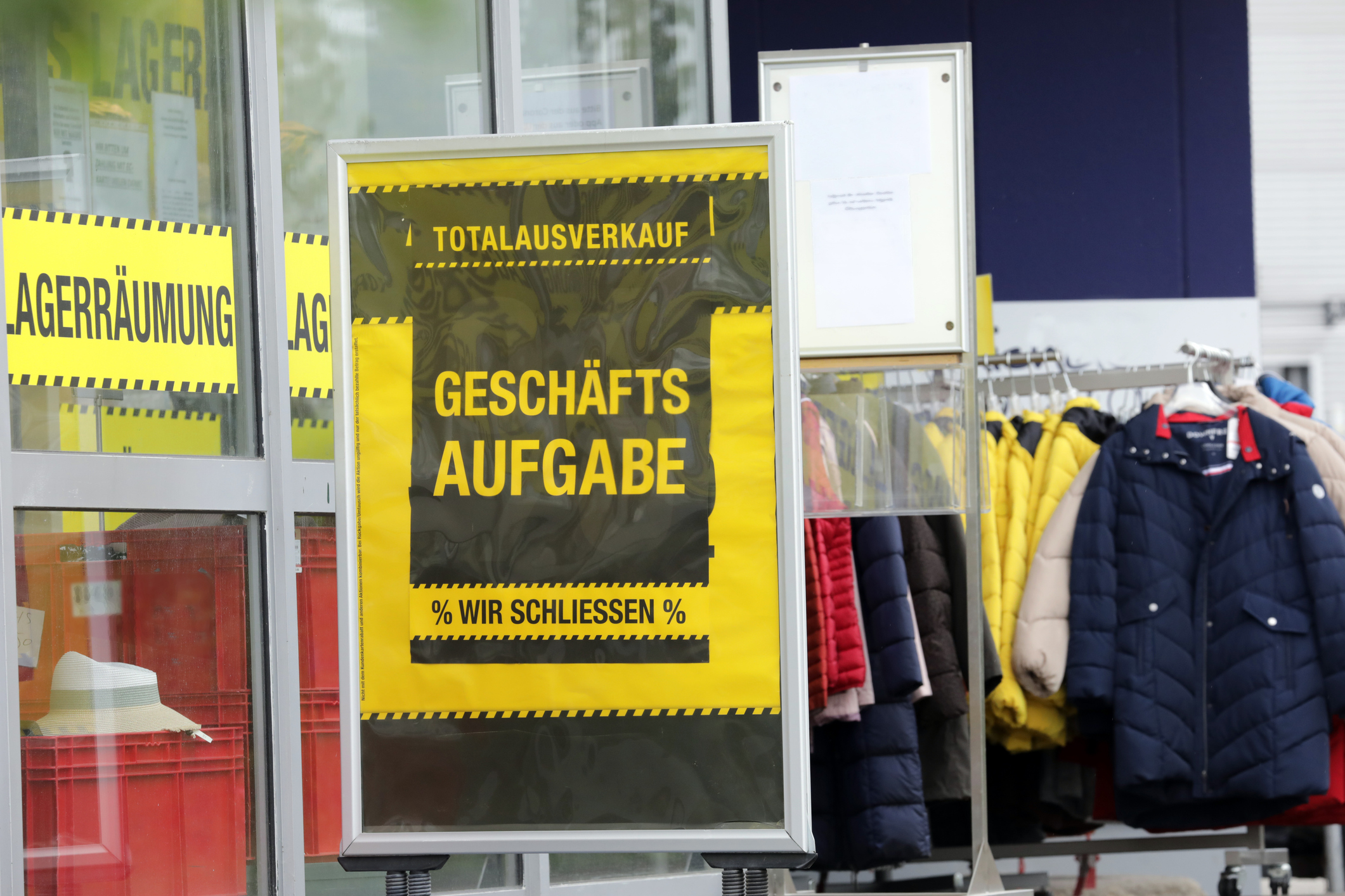 Vor einem Modegeschäft steht ein Schild mit der Aufschrift "Geschäftsaufgabe".
